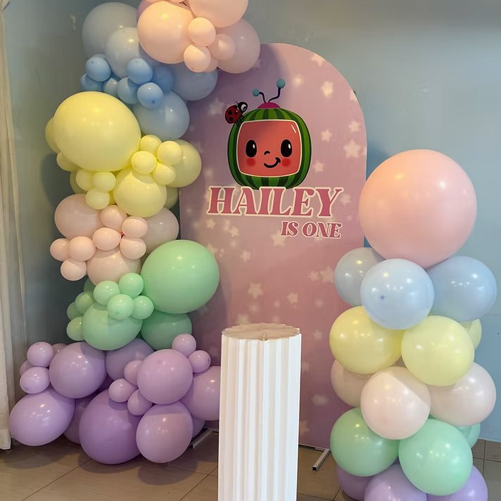 Custom printed foam board backdrop with a pastel rainbow Chiara garland and column