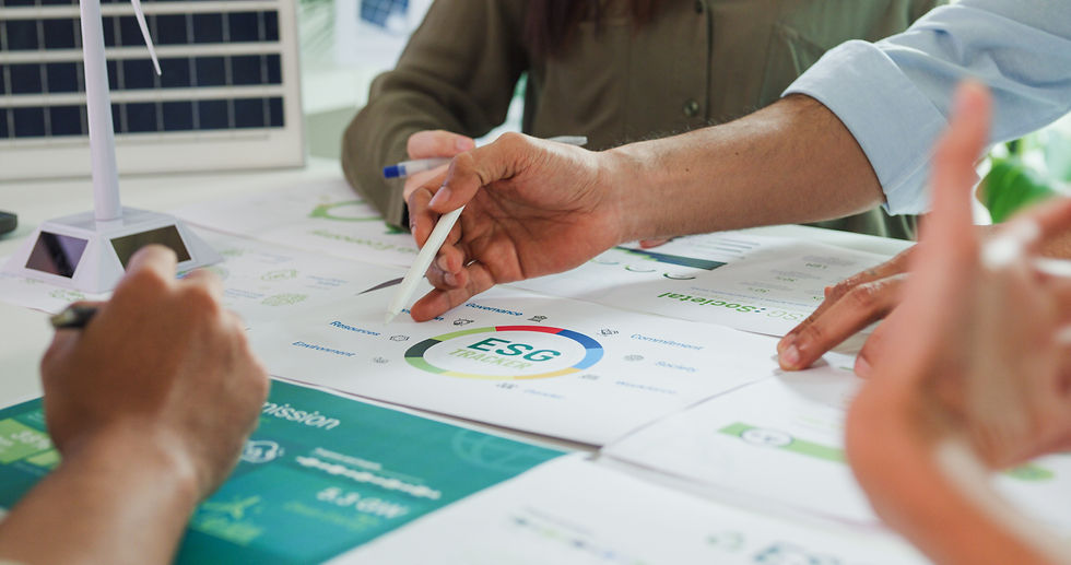 Hands pointing at ESG Tracker papers on a table, surrounded by documents and a small wind turbine model in a meeting setting.