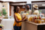 Women small business owner smiling holding food jars and two men having a conversation behind her