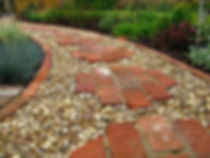 Cleaned recycled bricks used in pathway as stepping stone with brick edge filled with white pebble