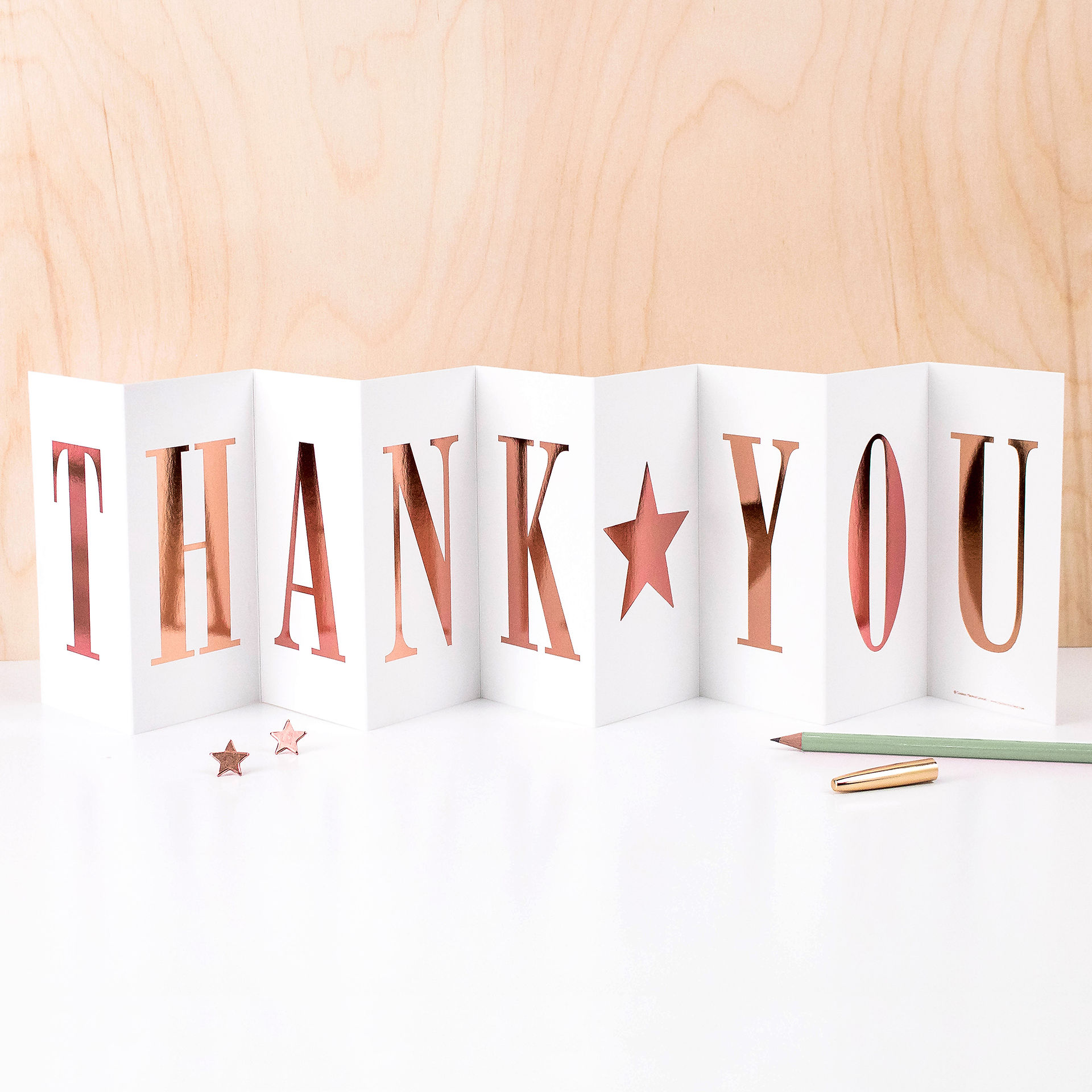 A fold out banner concertina card with the word thank you in rose gold metallic foil.