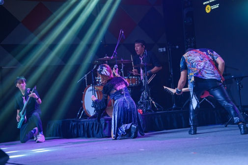 Hsachiko, daddy Wahyu, and daddy Ditto kneeling near drummer daddy Richi while performing on stage at Cosmic 2024.