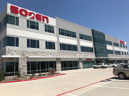 A 3 story gray professional building with stone facing, windows, and a red sign