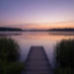 Wooden dock leading to a calm Virginia lake at sunset.