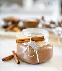 Short sealed mason jar with cinnamon stick and gift tag ties around it. Filled with diy body scrub.