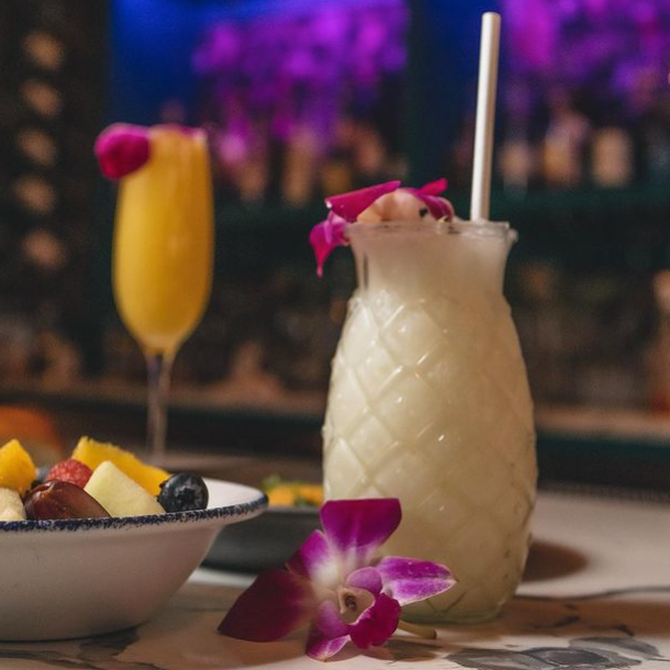 High angle view of a wooden table set with plates of Goan dishes and cocktails