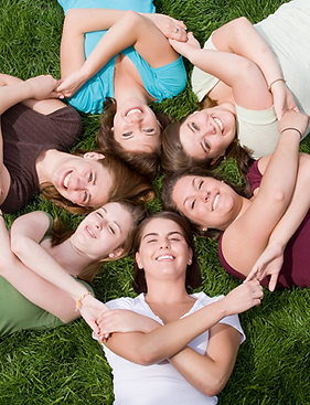 six girls holding hands while lying down in a circle on the grass