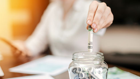 woman-dropping-banknotes-into-jar-with-rolled-banknotes-table-papers-table.jpg