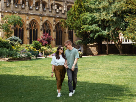 Couple walking together outside Cirencester Abbey during their engagement photoshoot