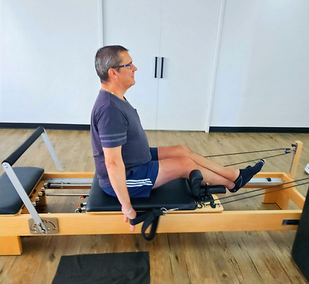 a middle aged man on a reformer pilates machine used on a page for pilates for over 50s