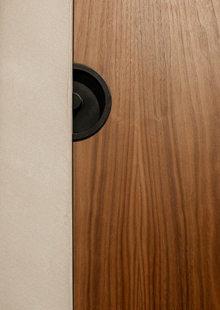 Detail van een houten maatwerkpaneel met geïntegreerd rond zwart element.