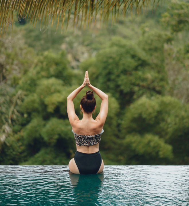 Woman in a yoga pose in an infinity pool overlooking the jungle during a wellness retreat in Costa Rica
