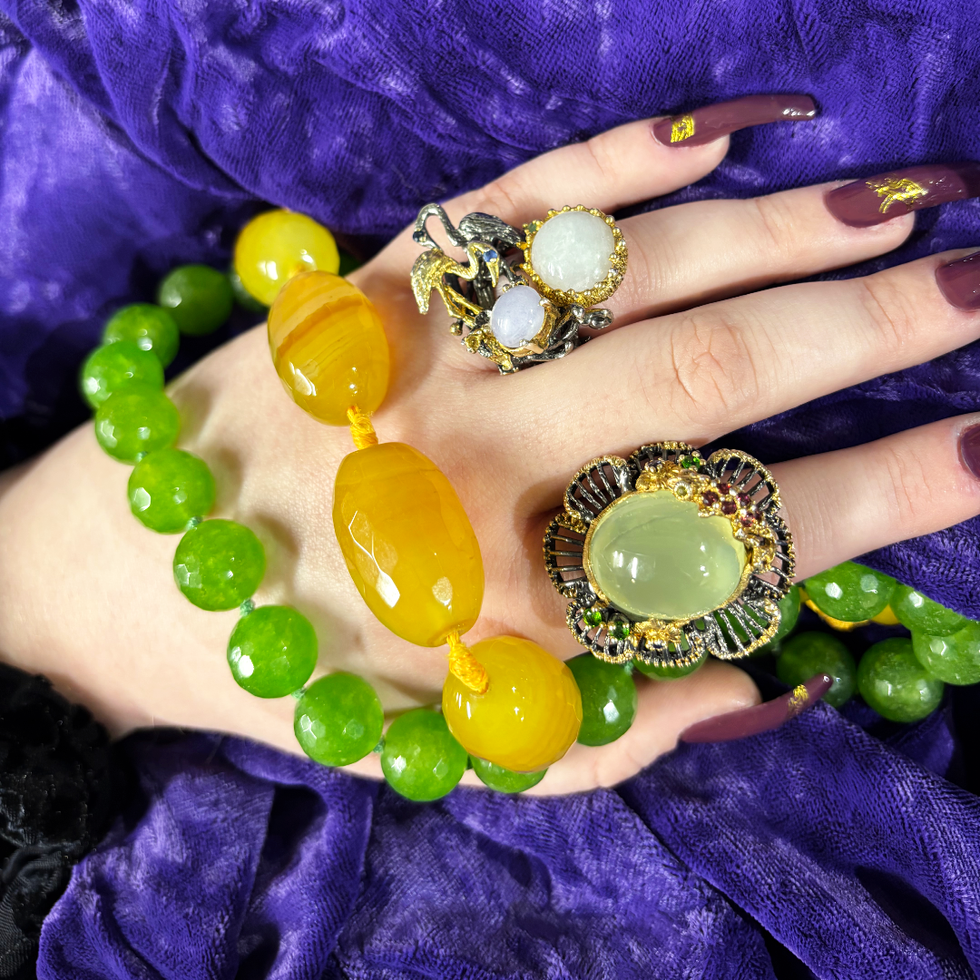 Green and yellow quartz necklaces pictured alongside flamingo and lizard rings.