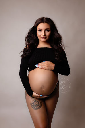 A stylish portrait of a mother-to-be in a chic black outfit, highlighting her radiance and confidence as she celebrates the beauty of pregnancy.