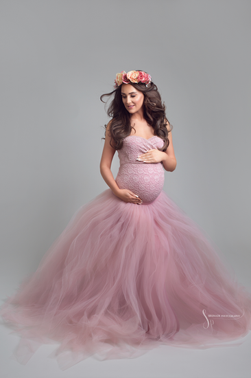 A dreamy maternity portrait featuring a mother-to-be in a pink tulle gown, surrounded by soft lighting, creating a graceful and elegant image.