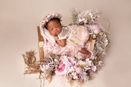 A peaceful newborn surrounded by soft florals, resting in a cozy floral nest with delicate pink and white tones, creating a dreamy and serene atmosphere.