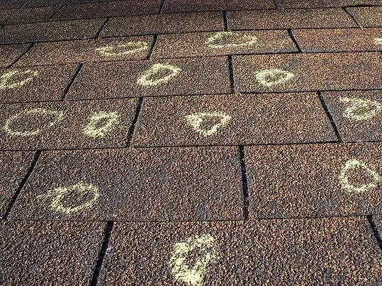 Roofing damage from a hail storm, marked with chalk by the insurance adjuster and during a free roof inspection