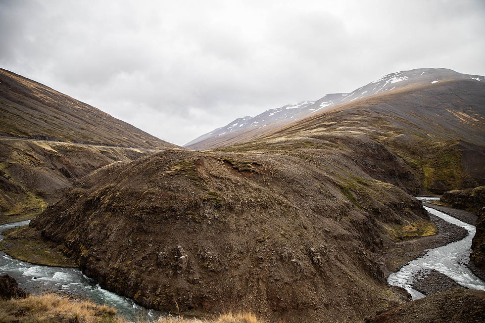 Milky blue glacial river trisecting pale green mountains at Öxnadalsheiði, Iceland