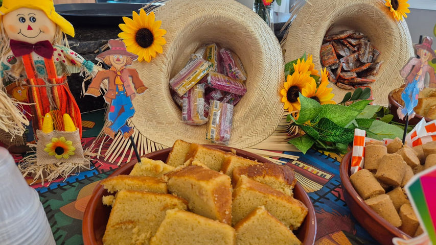 Comidas juninas como pamonha, canjica e bolo de milho servidas em buffet em casa
