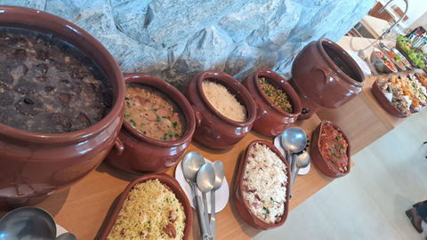 Mesa de feijoada com acompanhamentos servida em buffet a domicílio

