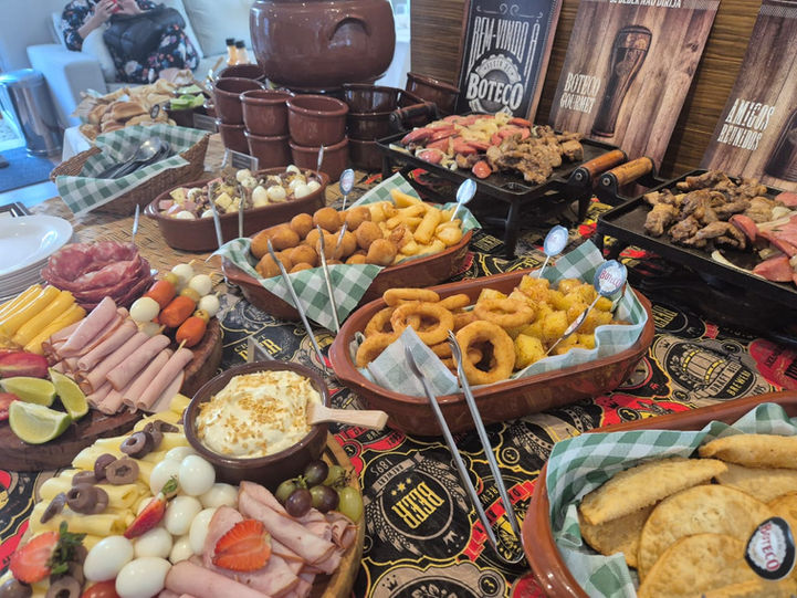 Buffet a domicílio com variedade de petiscos de boteco e bebidas refrescantes