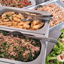 Mesa de saladas com folhas, legumes e molhos servida em buffet a domicílio para churrasco
