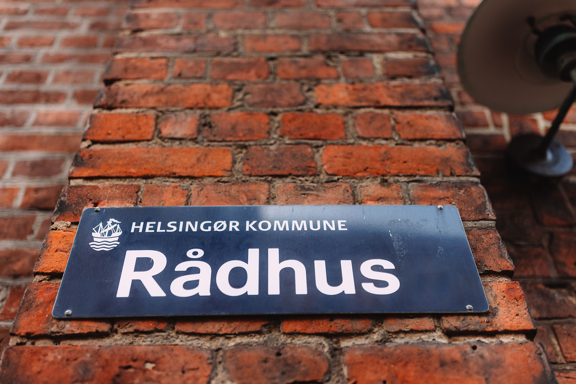 Close-up of the official 'Helsingør Kommune Rådhus' sign on a classic red brick wall.