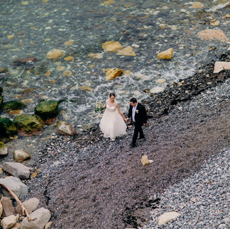 A couple holding hands while walking along the water's edge on the rocky beach at Stevns Klint.
