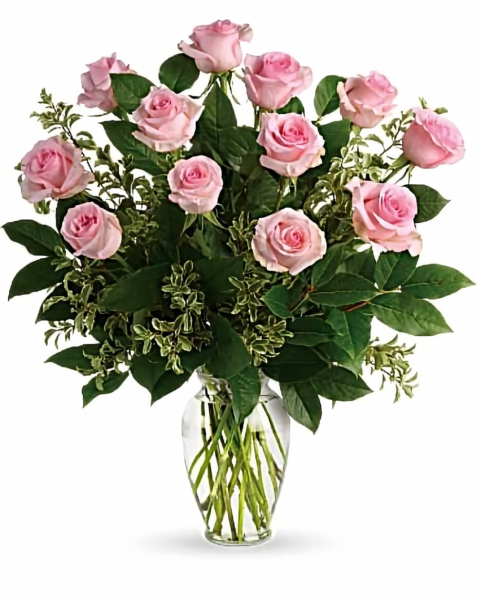 A selection of bright Pink Roses arranged in a glass vase with some filler greens.