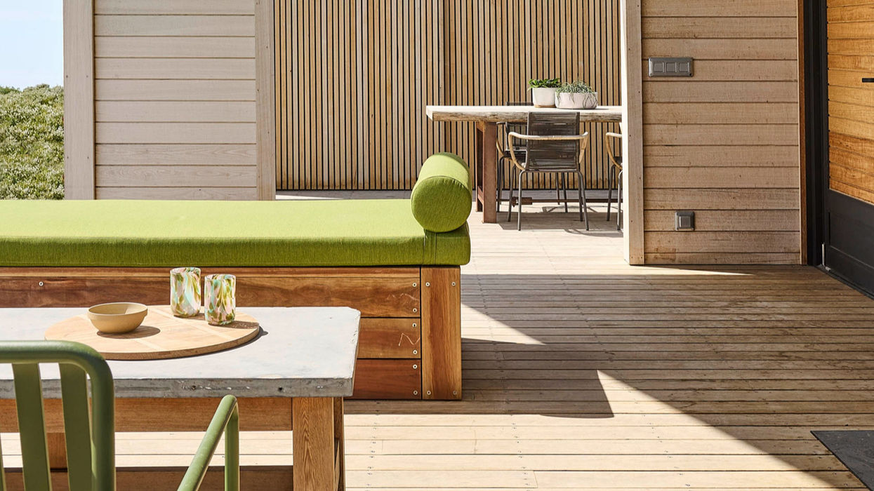 Outdoor wooden deck with green seating and table styled for a photoshoot