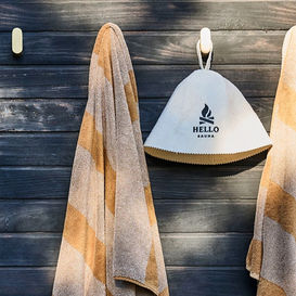 Towels and Hello Sauna hat hanging on wood