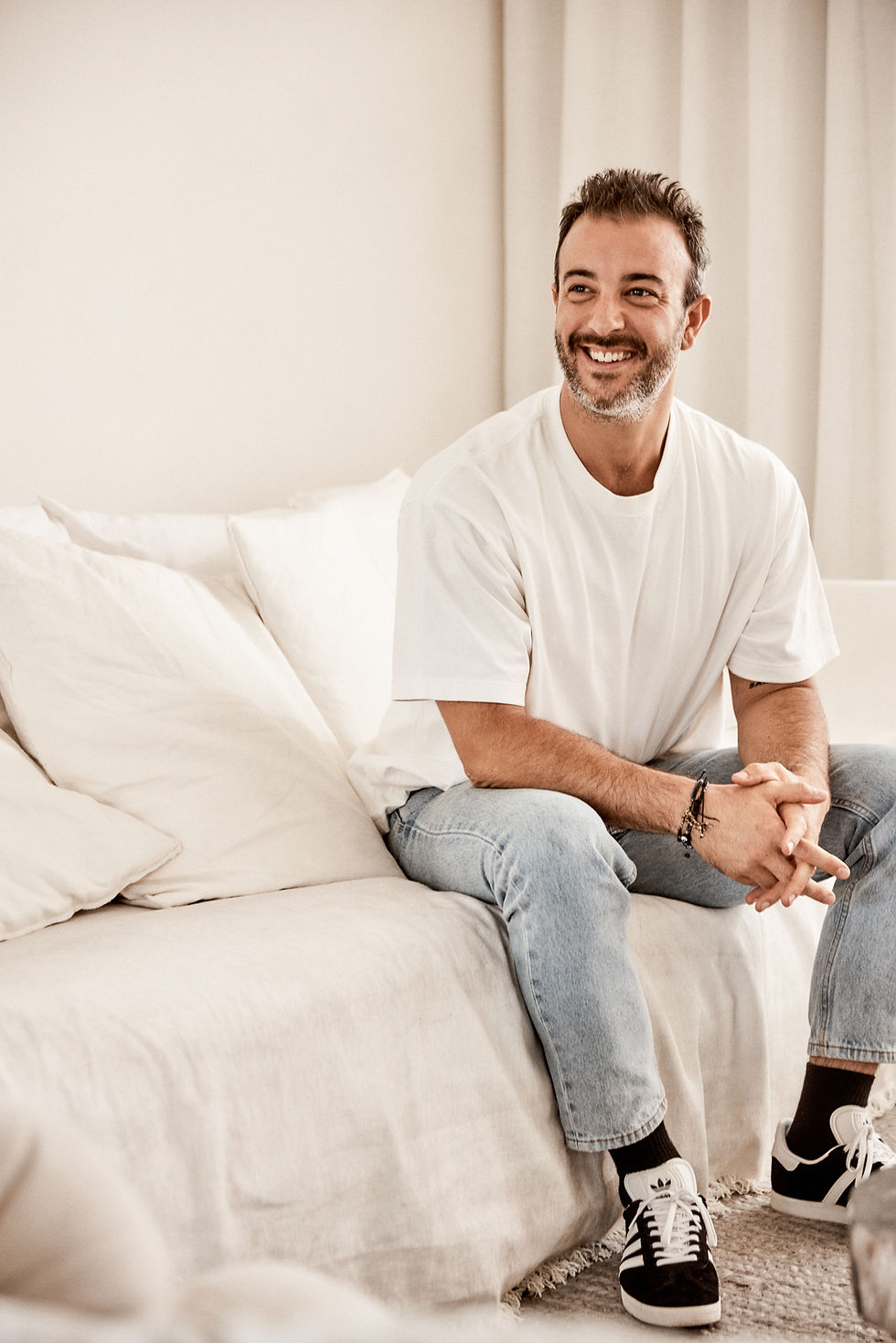 Yoga Teacher Nicky Grimsdale sitting on a sofa in a white room.