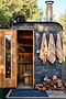 Outdoor wood sauna with open door, towels hanging