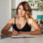 A woman is sitting in front of a book with a pen