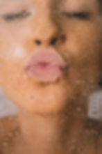 young woman kissing a window wearnign pale pink lipstick her eyes are closeded