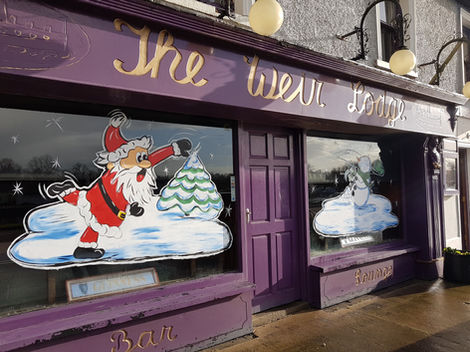 Pub window with two window paintings, one window is painted with Santa throwing a snowball, the other window is painted with a snowman getting hit in the face with the snowball.