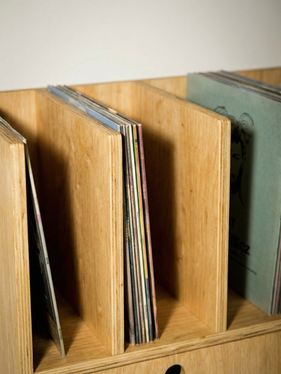 Close-up of vinyl record storage slots in a handmade plywood record player stand