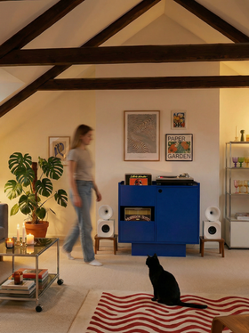 Living room setup with blue record player stand and vinyl storage, speakers and cozy home listening corner
