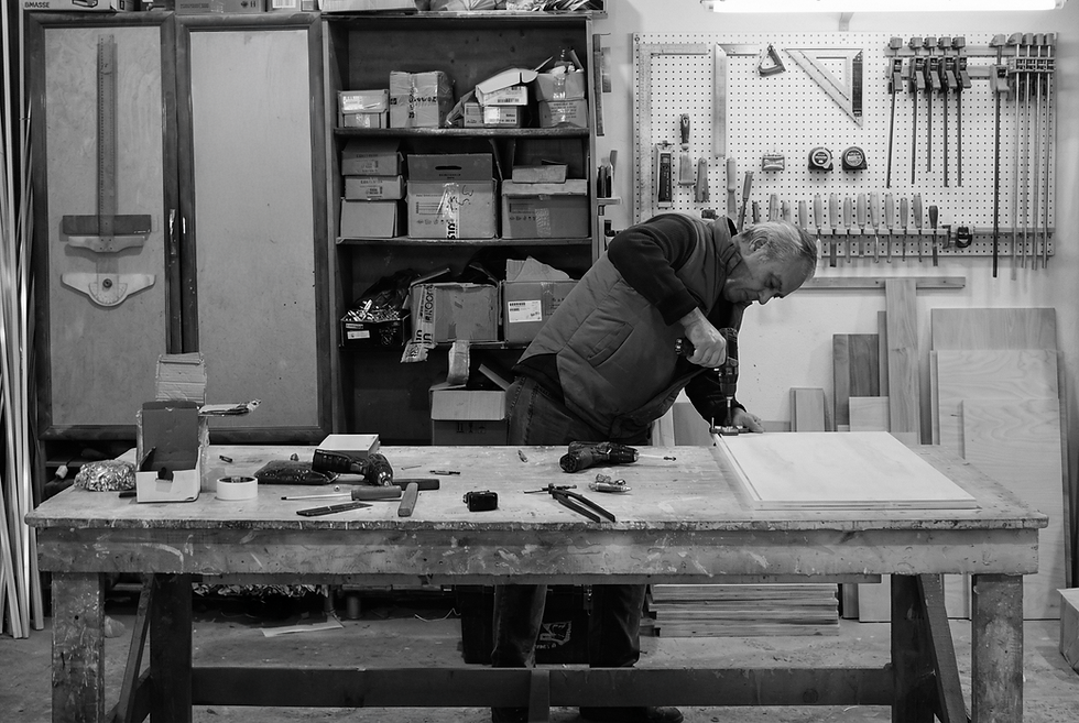 Groove Wood Studio workshop in Mersin, Türkiye, craftsman drilling holes in birch plywood at a large workbench with hand tools on the wall