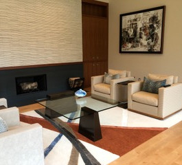 Contemporary living room with light colored upholstery, thick glass cocktail table held precariously by metal stands and abstract artwork.