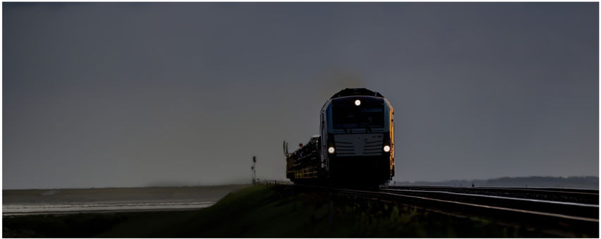 A train in germany catches a small glint as it pulls a car train across the causeway that links the island of Sylt to Germany.