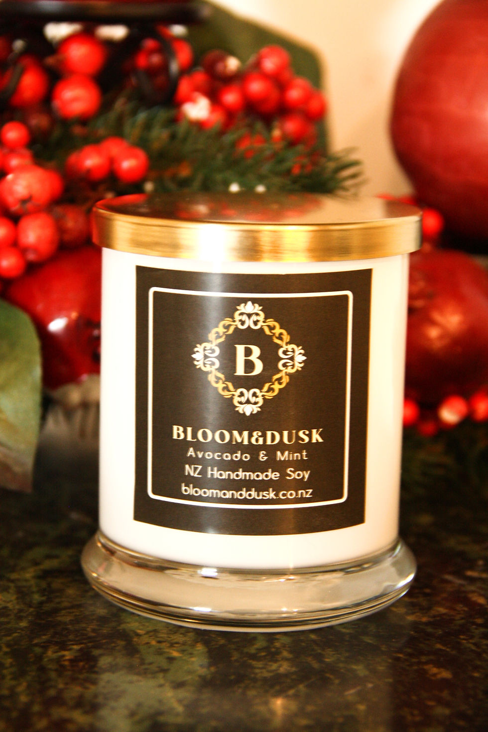 Avocado and mint candle in gorgeous glass jar with gold lid with mistletoe behind it