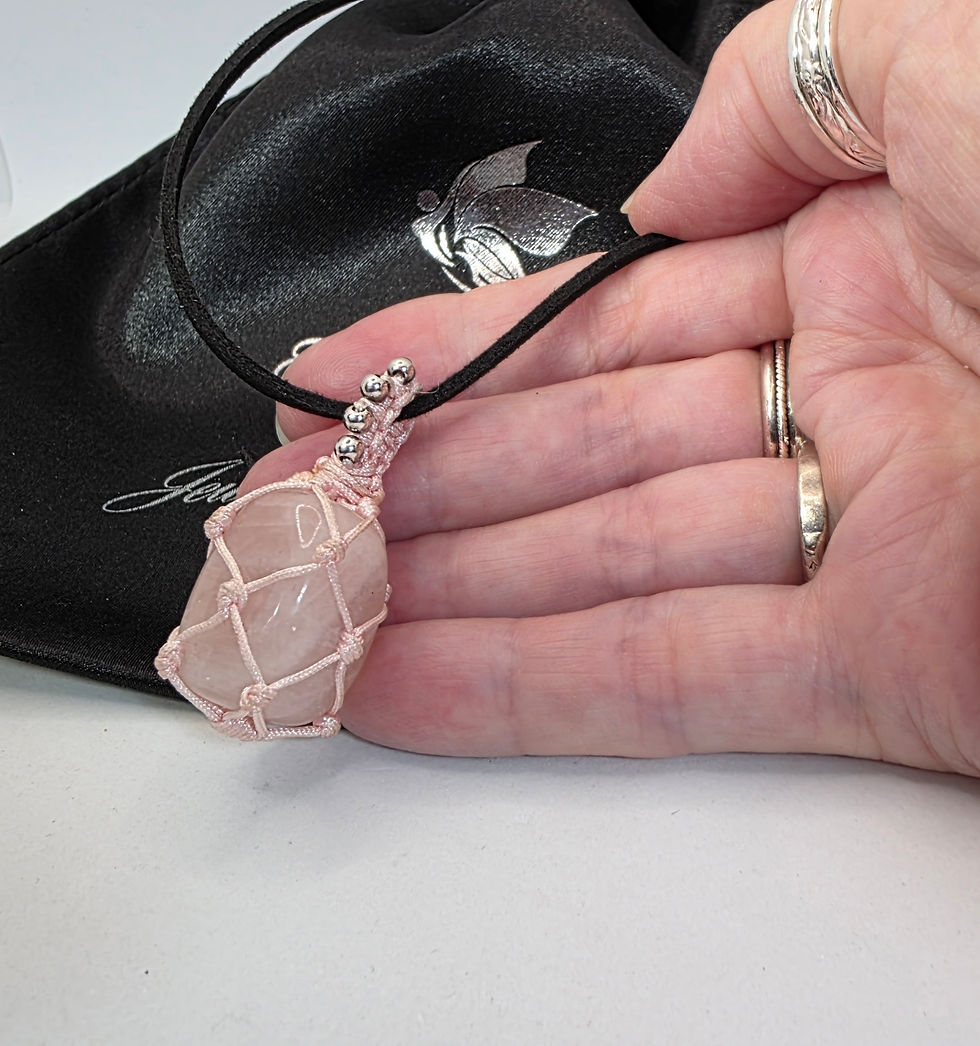 Thumbnail: Hand showing macrame wrapped rose quartz pendant on black cord