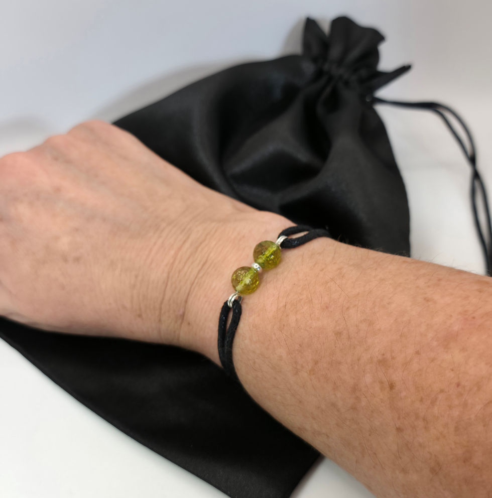 Thumbnail: Black cord bracelet with peridot beads, displayed on women's wrist
