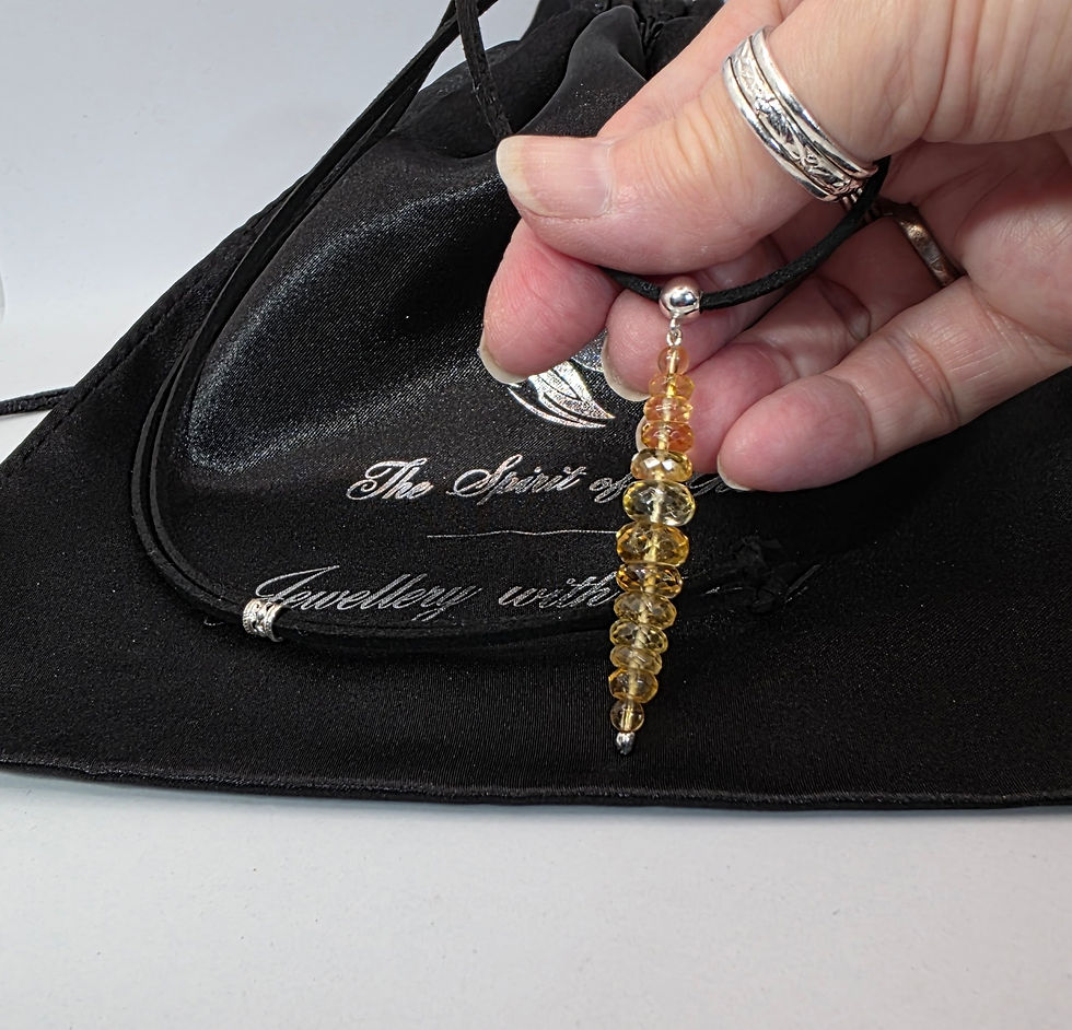 Citrine pendant on black cord, displayed on black satin pouch