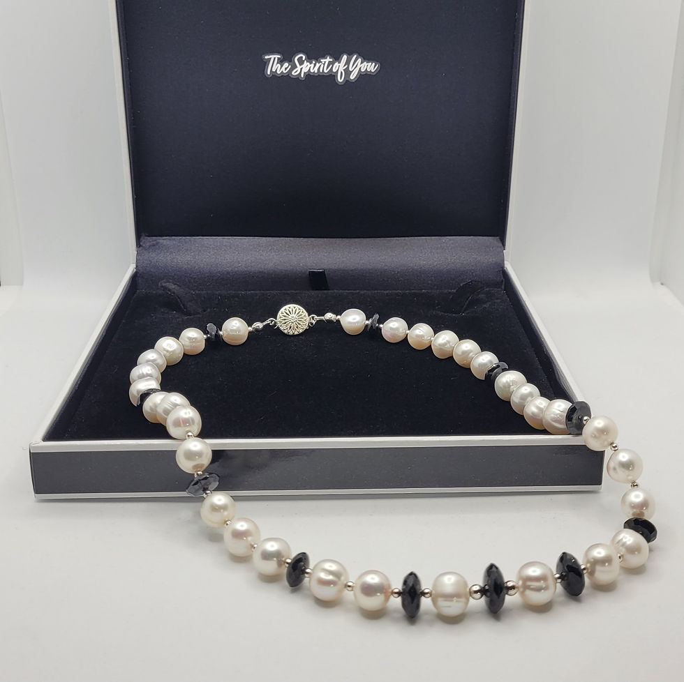 Large white freshwater cultured pearl necklace with black spinel beads displayed on gift box