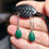 Thumbnail: Hand holding Malachite and sterling silver earrings on black display stand