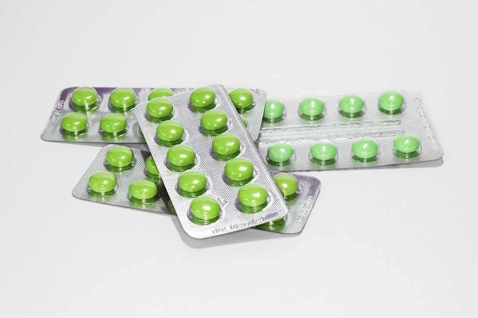 Several foil and plastic blister packs, each containing multiple round, bright green pills, are stacked on a white surface.