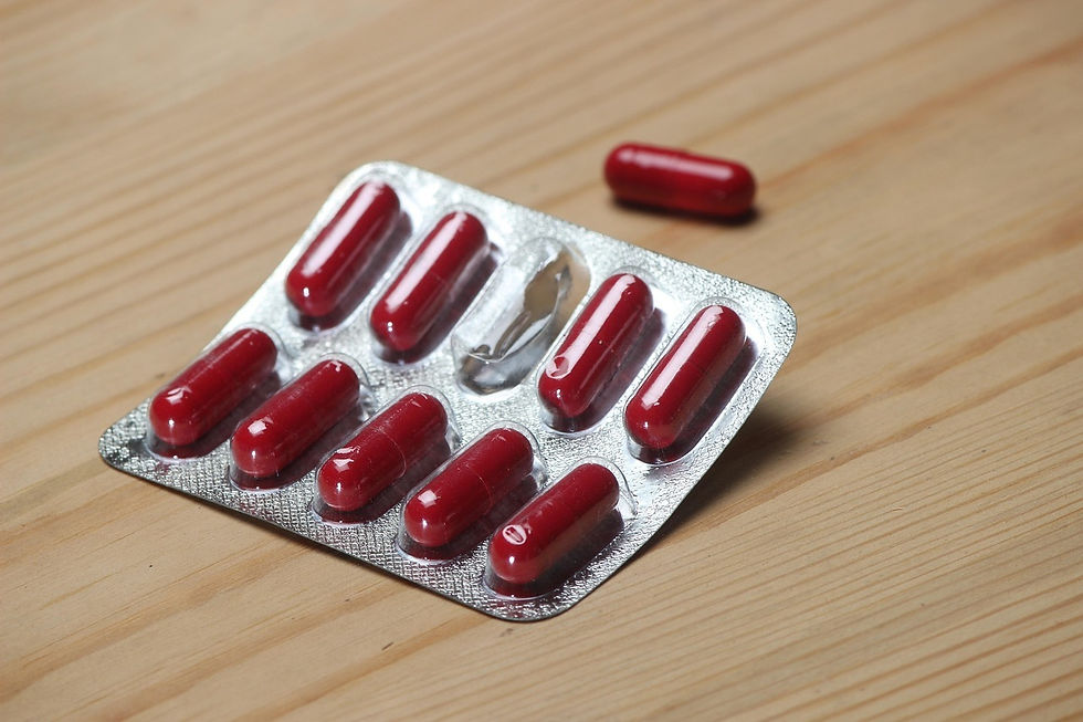 A blister pack of shiny red capsules rests on a light wood-grain surface