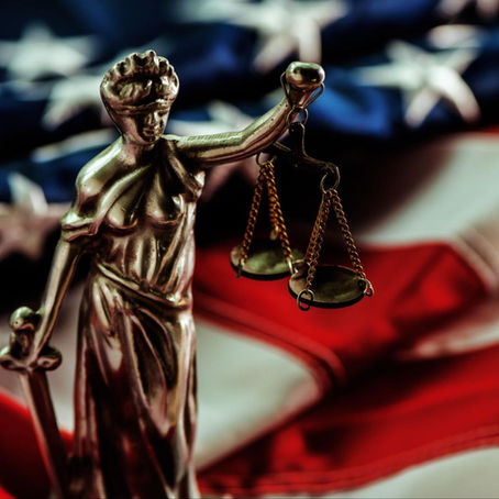 statue of Lady Justice in front of American flag, representing criminal justice grant help for DA offices